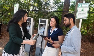 Leila Hajibabai working with two of her research students at an EV charging station