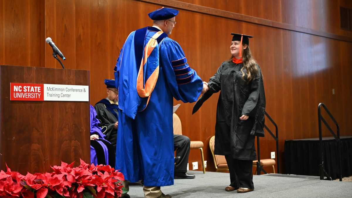On stage, Madeline Hendley shakes hands with Russell King