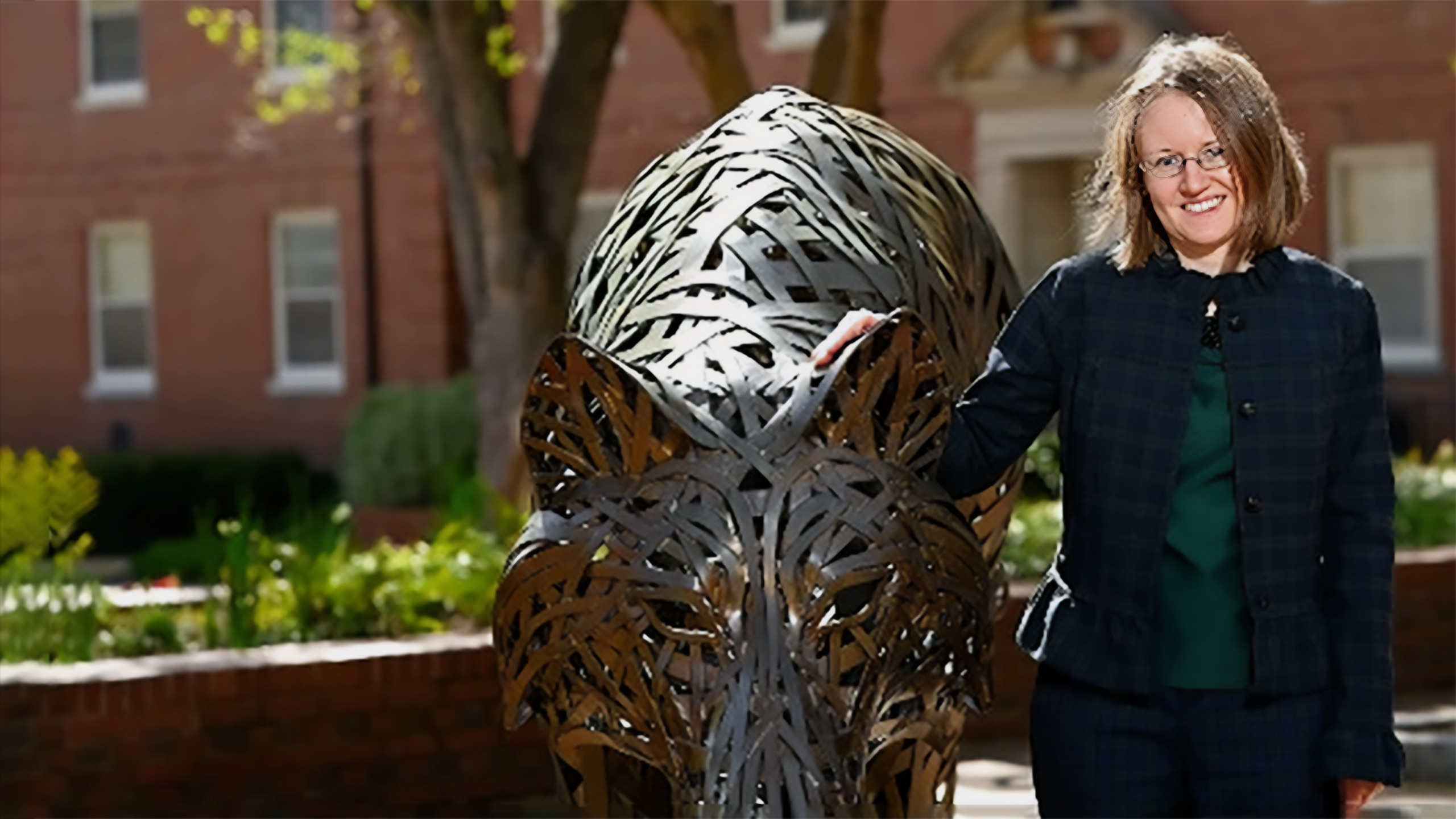 Katie Homar standing next to one of the copper wolf statues on NC State's campus