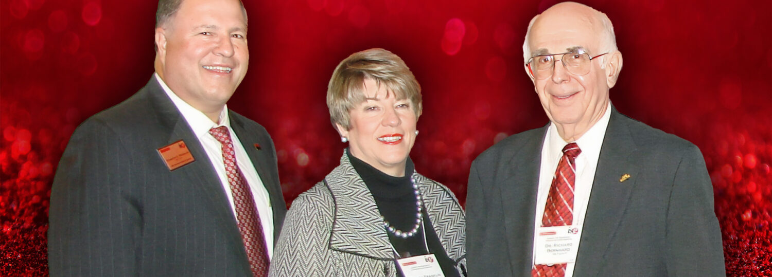 Dick Franklin, Wanda Franklin and Dick Bernhard standing in front of a red background