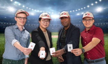 ISE new faculty members Jordan Kern, April Yu, Fred Livingston and Adolfo Escebedo standing in the outfield of a baseball stadium each holding an ace card.