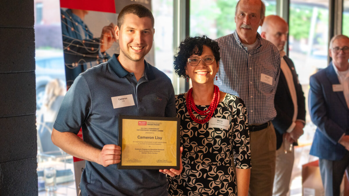 Ph.D. student Cameron Lisy accepting the Salah E. Elmaghraby Distinguished Student Award from OR director Maria Mayorga.